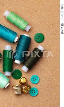 Spools of thread and buttons spread on a craft workspace at midday 138801882