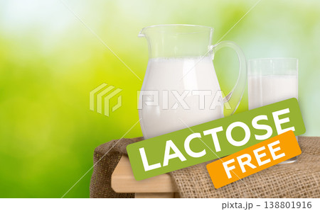 Lactose free milk jug and glass on wooden table with green background Lactose free milk jug and glass on wooden table with green background 138801916