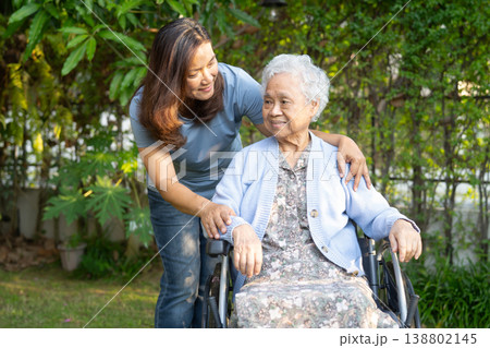 Caregiver help Asian elderly woman disability patient sitting on wheelchair in park. 138802145