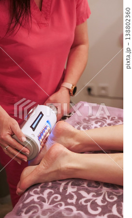 Feet massage. Endosphere therapy. Female beautician using therapeutic apparatus compressive microvibration electronic device. 138802360
