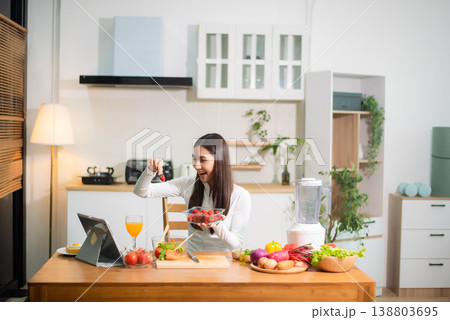 Healthy Asian woman mixing fresh salad at home kitchen with vegetables and juice. Clean eating, meal prep, nutrition diet, wellness lifestyle 138803695
