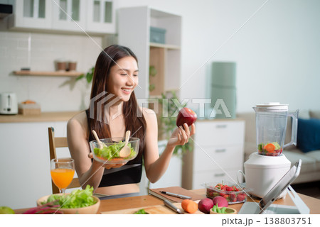 Asian woman preparing fresh salad with vegetables in modern kitchen. Clean eating, healthy lifestyle, nutrition and fitness food concept at home. Asian woman preparing fresh salad with vegetables in modern kitchen. Clean eating, healthy lifestyle, nutrition and fitness food concept at home. 138803751
