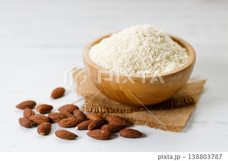 Almond meal, Almond flour, in wooden bowl with almond nuts on white table. 138803787