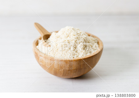 Almond meal, Almond flour, in wooden bowl with almond nuts on white table. Almond meal, Almond flour, in wooden bowl with almond nuts on white table. 138803800