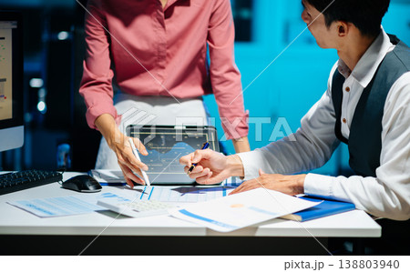 Business documents on office table with smart phone and laptop and two colleagues discussing data in the background Business documents on office table with smart phone and laptop and two colleagues discussing data in the background 138803940