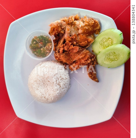 fast food fried chicken with raw chili sauce, cucumber slices and rice balls, also called ayam penyet in Indonesia fast food fried chicken with raw chili sauce, cucumber slices and rice balls, also called ayam penyet in Indonesia 138804341