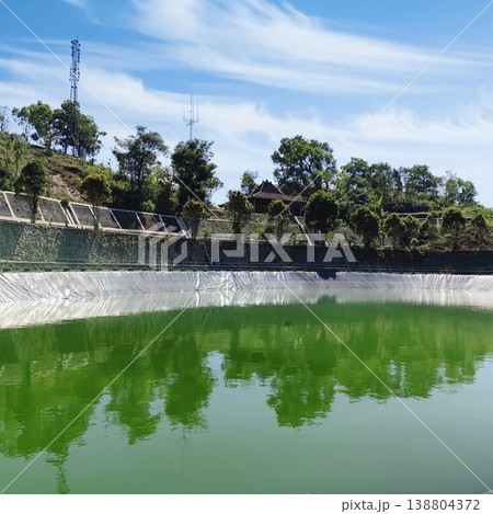 beautiful view of embung or artificial lake at the top of the hills with a bright blue sky 138804372