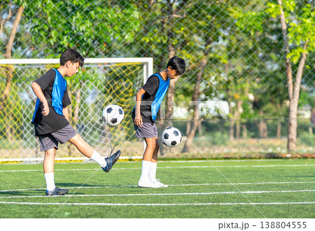 Two boys are juggling a soccer ball in the field to practice and prepare for competition with day light. Two boys are juggling a soccer ball in the field to practice and prepare for competition with day light. 138804555