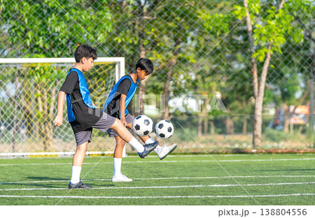 Two boys are juggling a soccer ball in the field to practice and prepare for competition with day light. Two boys are juggling a soccer ball in the field to practice and prepare for competition with day light. 138804556