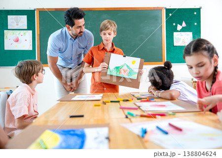 The teacher stand beside and try to make a boy with blond hair present his drawing or painting in front of the classroom and also ask the idea or the meaning of the picture. The teacher stand beside and try to make a boy with blond hair present his drawing or painting in front of the classroom and also ask the idea or the meaning of the picture. 138804624