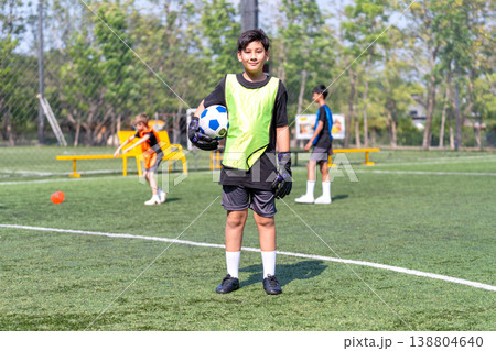 Portrait of a boy hold the soccer ball and stand in the field also look at camera during practice for the competition. Portrait of a boy hold the soccer ball and stand in the field also look at camera during practice for the competition. 138804640