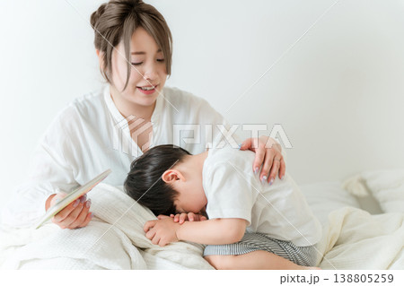 ベッドで子供に絵本を読んであげる母親（寝かしつけ,お昼寝,読み聞かせ） 138805259