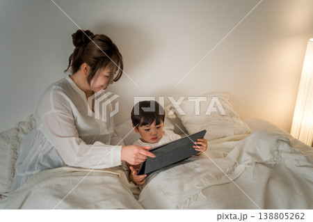 ベッドで子供にタブレットで絵本を読んであげる母親(寝かしつけ,お昼寝,読み聞かせ) ベッドで子供にタブレットで絵本を読んであげる母親(寝かしつけ,お昼寝,読み聞かせ) 138805262