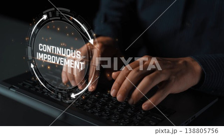 Close-up of hands typing on a keyboard with a futuristic digital interface highlighting the concept of continuous improvement in a dark, professional setting. Sigmoid 138805756