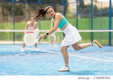 Adult woman plays paddle tennis against team of women Adult woman plays paddle tennis against team of women 138806302