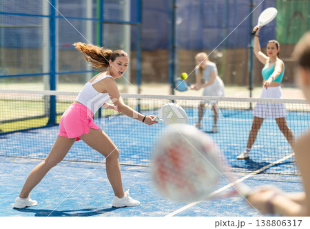 Young woman playing paddle tennis against team of women 138806317