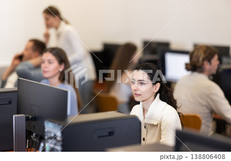 Girl student of computer courses looks at monitor screen, types on keyboard and does work Girl student of computer courses looks at monitor screen, types on keyboard and does work 138806408