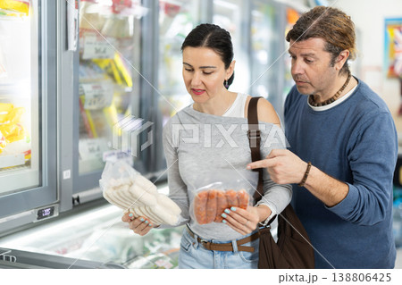 Couple in supermarket choose cooled raw sausages 138806425
