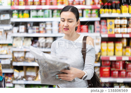Woman customer in supermarket choose dried fish, buy food stuff in grocery store Woman customer in supermarket choose dried fish, buy food stuff in grocery store 138806569