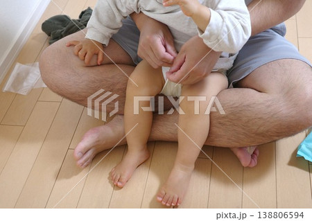 家で座って子どものおむつ替えをするパパ 138806594