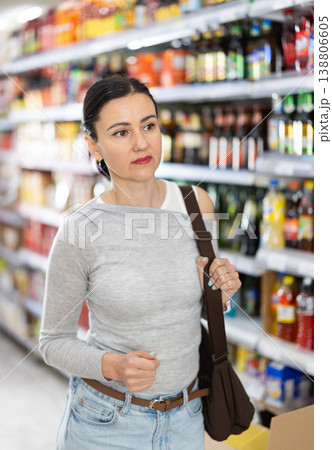 In food store, woman looking for something on shelf of showcase 138806605