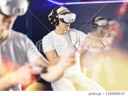 In darkened hall of gaming club, guy in VR helmet takes part in group game In darkened hall of gaming club, guy in VR helmet takes part in group game 138806633