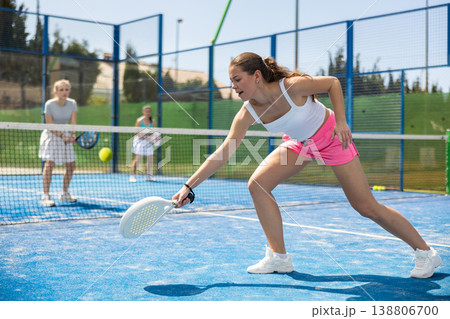 Young woman playing paddle tennis against team of women 138806700