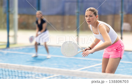 Woman standing behind net on tennis court 138806703