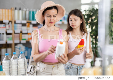 Mom and daughter choosing sunscreen in chemist's shop 138806822