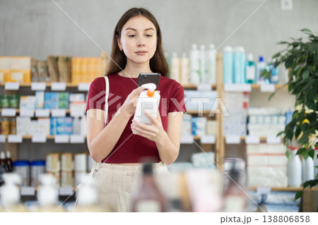 Young woman scanning QR-code on cream in drugstore Young woman scanning QR-code on cream in drugstore 138806858