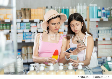 Woman and girl daughter in pharmacy scans QR code on sun protection cream Woman and girl daughter in pharmacy scans QR code on sun protection cream 138806987