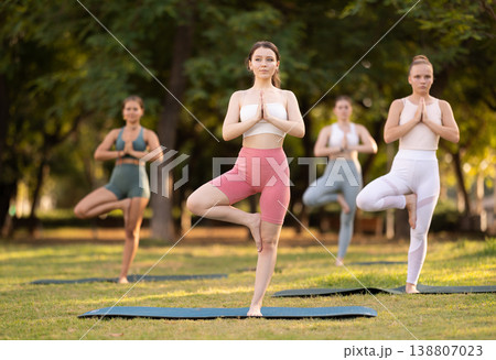 Yoga lesson visitors girls perform vrikshasana in park 138807023