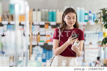 Woman in pharmacy scans QR code on antidandruff shampoo Woman in pharmacy scans QR code on antidandruff shampoo 138807027
