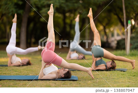 Yoga lesson visitors girls perform Salamba Sarvangasana in park 138807047