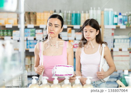 Positive mother and daughter standing at pharmacy or department of household chemicals, choosing feminine pads 138807064