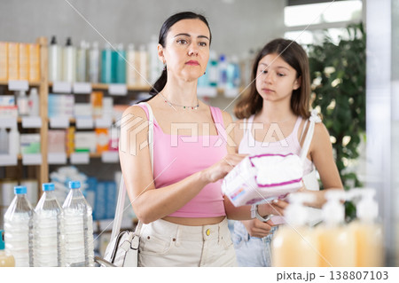 Mom and daughter in summer clothes choosing feminine pads in chemist's shop Mom and daughter in summer clothes choosing feminine pads in chemist's shop 138807103