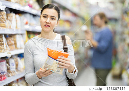Woman in supermarket choose groats Woman in supermarket choose groats 138807113