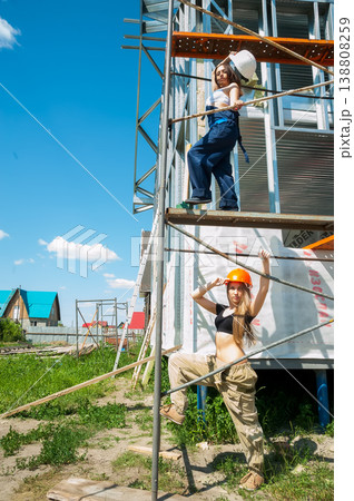 Two women in hard hats standing on scaffolding at a residential construction site, safety and teamwork concept 138808259