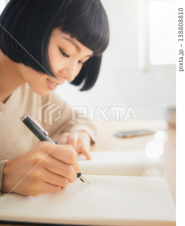 ノートに万年筆で書く女性の手元と横顔 138808810