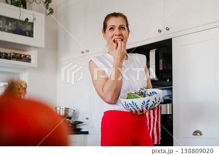 Woman tasting fresh salad while cooking healthy meal. Woman tasting fresh salad while cooking healthy meal. 138809020