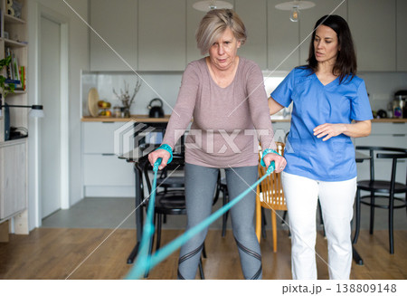 Physiotherapist guiding senior woman during resistance band exercise. Physiotherapist guiding senior woman during resistance band exercise. 138809148