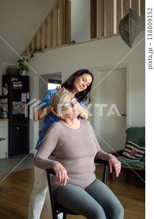 Physiotherapist helping senior woman with neck exercise, home therapy session. Physiotherapist helping senior woman with neck exercise, home therapy session. 138809152
