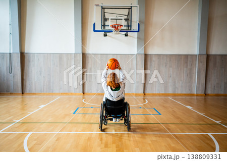 Wheelchair basketball player shooting ball towards hoop. Wheelchair basketball player shooting ball towards hoop. 138809331