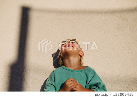 Smiling blond child wearing round sunglasses in warm sunlight. 138809419
