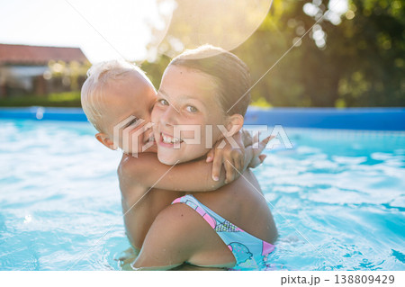 Sister and toddler brother playing in swimming in pool. Sister and toddler brother playing in swimming in pool. 138809429