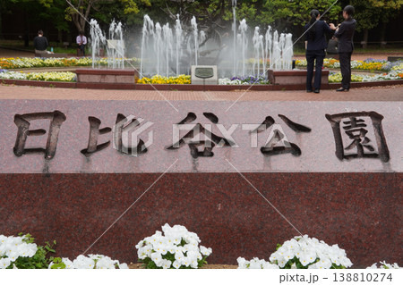 日比谷公園の入り口銘板と噴水の広場で憩う人々 138810274