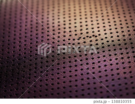 Close-up view of textured purple leather material with perforated holes, showcasing the intricate design and craftsmanship of the fabric surface 138810355