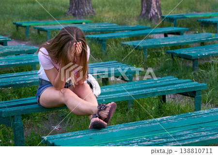 Sad disappointed young woman sits on bench in summer park Sad disappointed young woman sits on bench in summer park 138810711