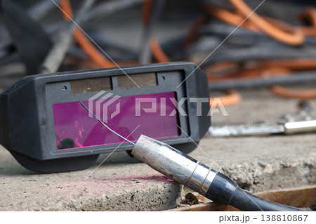 Close-Up Of Welding Goggles and Electrode With Welding Cable On Concrete Surface Close-Up Of Welding Goggles and Electrode With Welding Cable On Concrete Surface 138810867
