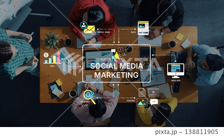 Group of Diverse People Collaborating on Social Media Marketing Strategy at a Wooden Table with Digital Tools and Charts Trope Group of Diverse People Collaborating on Social Media Marketing Strategy at a Wooden Table with Digital Tools and Charts Trope 138811905